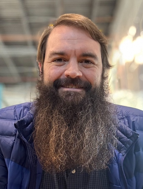 A photo of Steve Sadler, an assistant coach of the Ridgeline MTB Team. He is smiling and wearing a Ridgeline MTB team jersey.